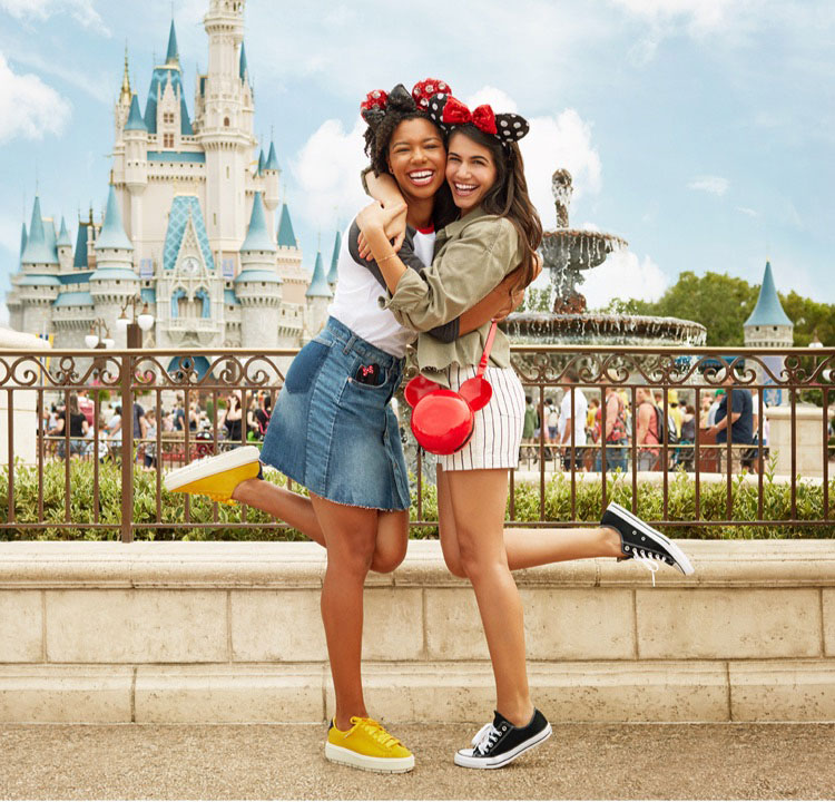 Two girls hugging in front of a Disney Castle