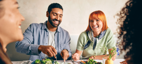 Group of four adults smiling and enjoying a meal together at a table