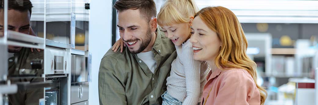 A young family of three checking out appliances at the department store