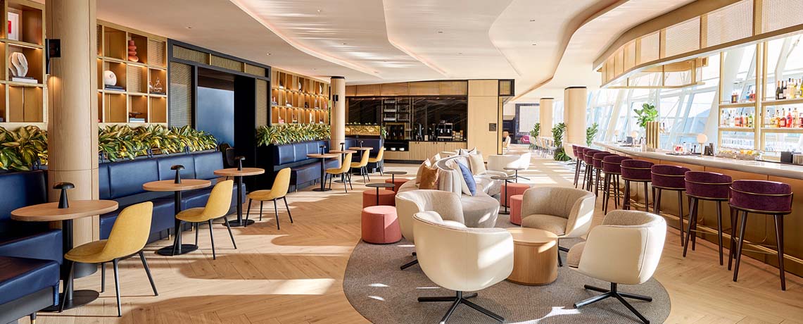 Sapphire Lounge at John F. Kennedy International Airport, New York, with round tables, armchairs, a bar area, and large windows.