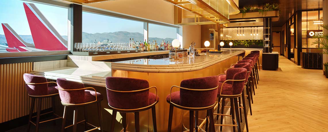 Sapphire Lounge at Phoenix Sky Harbor International Airport with a curved bar counter, purple stools, and large windows with runway views.