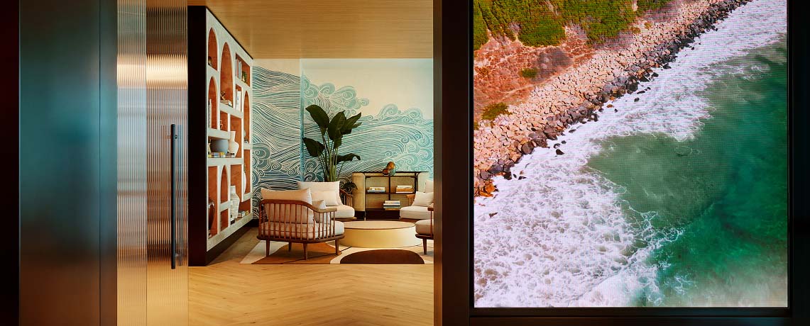 Sapphire Lounge at San Diego International Airport with contemporary furniture and a large mural of ocean waves.