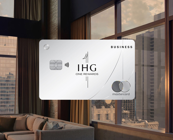 IHG One Rewards Premier Business credit card displayed in front of a modern hotel room with city views